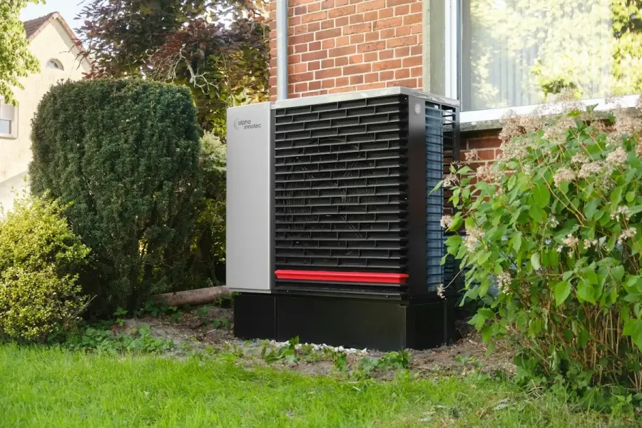 Outdoor cold-climate air source heat pump unit installed beside a brick home in Atlantic Canada